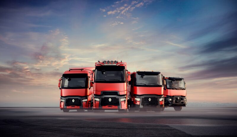 Four red Renault trucks underneath a sunset