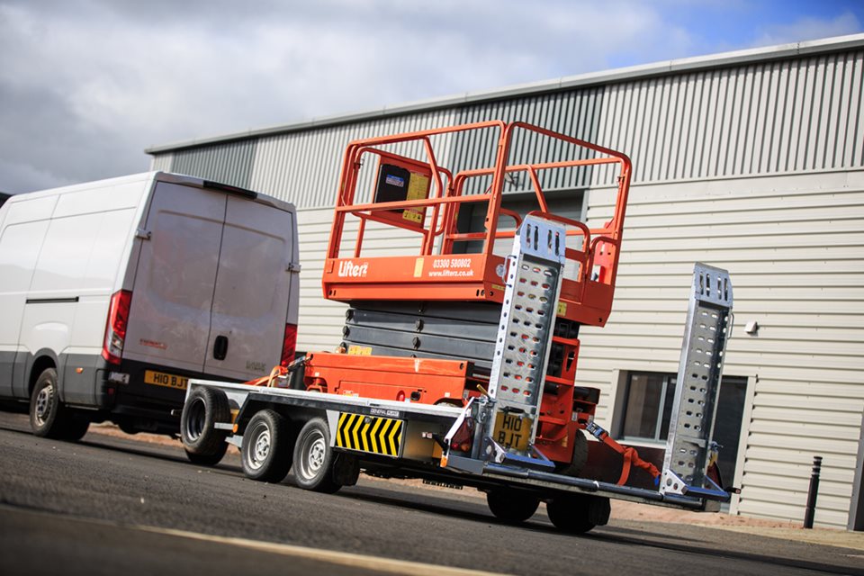 A Brian James Eco Plant Trailer carrying a scissor lift. It is being towed by a van. It is part of the commercial trailer range. 